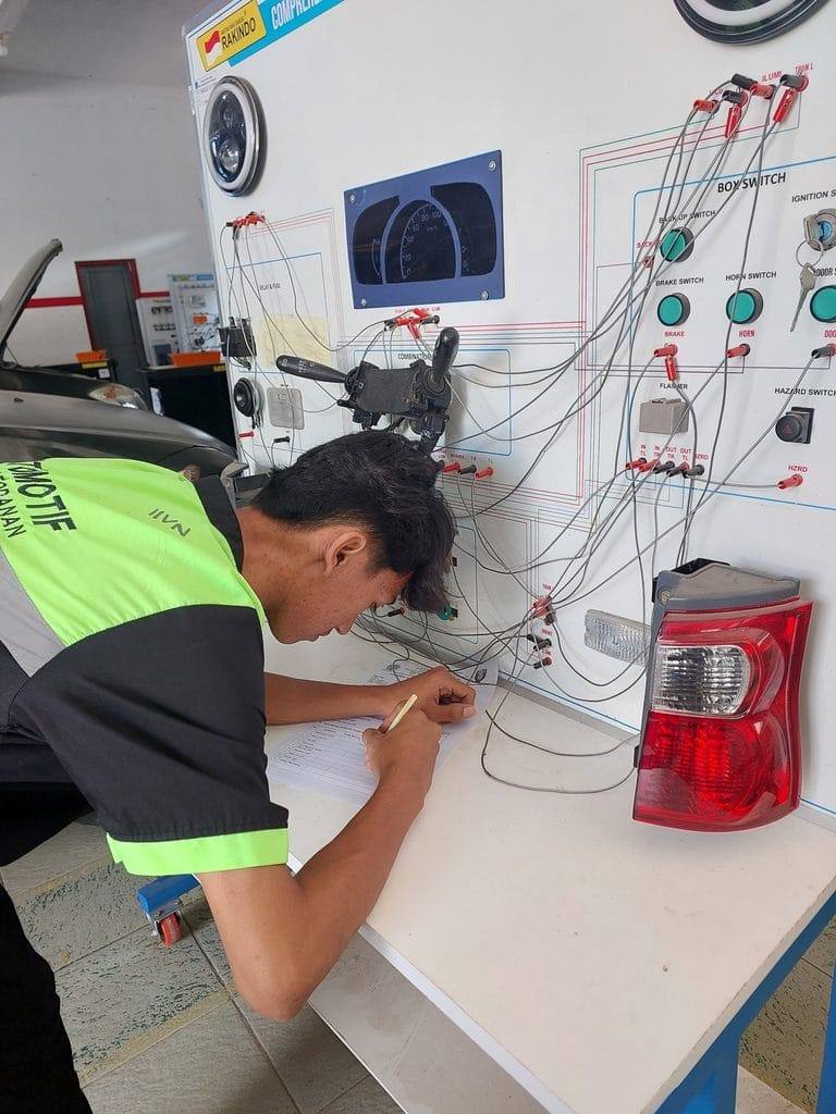 Siswa TKR mengerjakan asesmen pada trainer kelistrikan otomotif